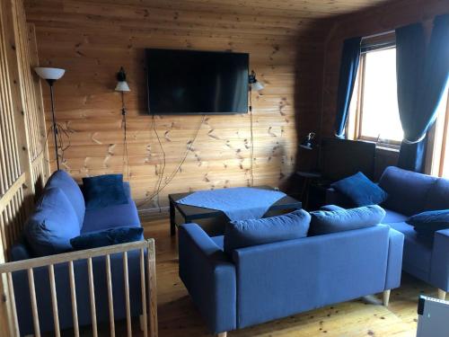 a living room with blue couches and a flat screen tv at Holiday Home Kalavåg by Interhome in Kalavåg