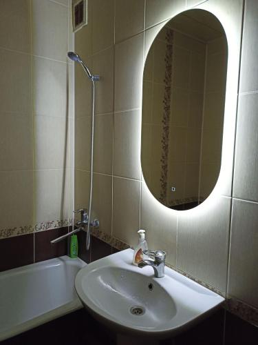 een badkamer met een wastafel, een spiegel en een bad bij Трешка на Автовокзале in Qizilorda