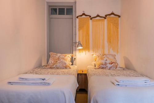 リスボンにあるCondessa Doll's Houseの白いシーツが備わるベッド2台が備わる客室です。