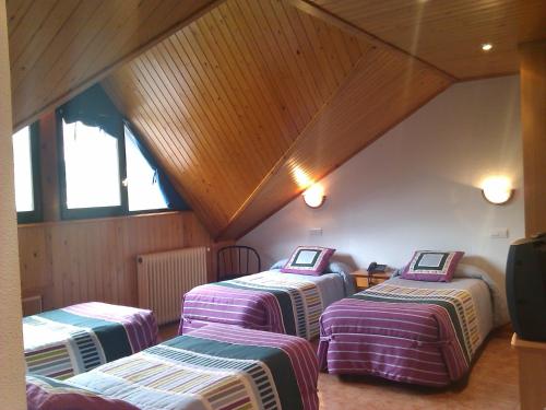 three beds in a room with a attic at Hotel Tirol in Formigal