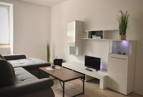 sala de estar con sofá y escritorio con TV en Schneiders Ferienwohnung 2, en Braunshausen