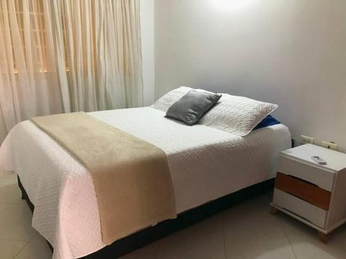 a bed with a pillow and a nightstand next to a window at Acogedor apartamento en Barrancabermeja in Barrancabermeja