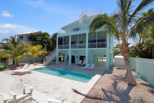 a large blue house with a swimming pool and palm trees at Conch Bar South in Tavernier