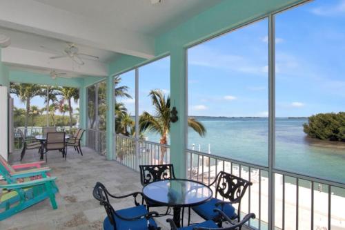 a balcony with a table and chairs and the ocean at Conch Bar South in Tavernier