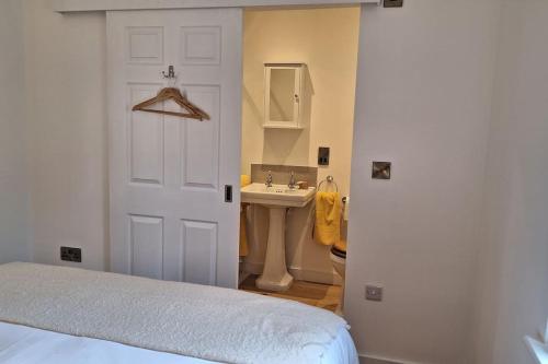 a bedroom with a bed and a sink and a door at Rural Cornish Cottage in Truro