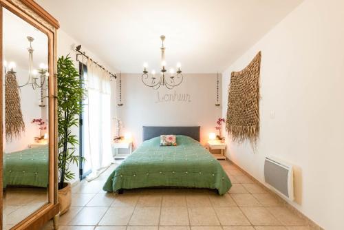 - une chambre avec un lit vert et un grand miroir dans l'établissement L'ETOURNEAU, à Bédoin