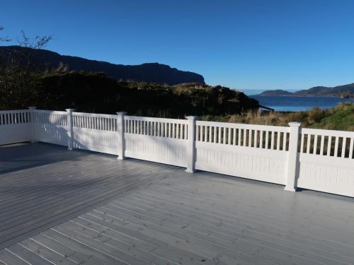a white fence on a deck with a view of the water at Holiday Home Sjøtun - FJS155 by Interhome in Hyllestad