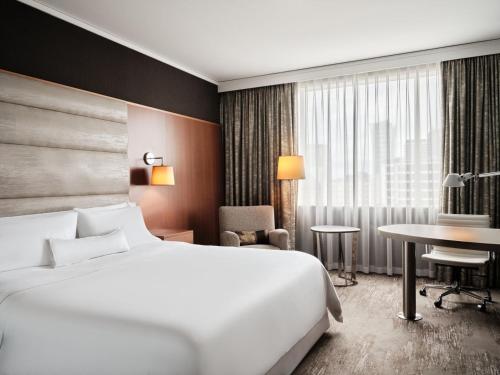 ワルシャワにあるザ ウェスティン ワルシャワの大きなベッドとテーブルが備わるホテルルームです。