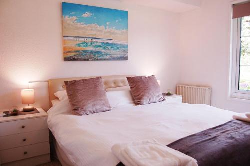 Un dormitorio con una cama blanca y una pintura en la pared en Hafan Y Talgarth bungalow at Plas Talgarth resort, en Pennal