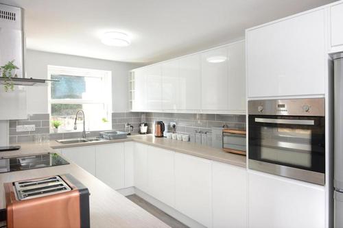 uma cozinha com armários brancos e electrodomésticos de aço inoxidável em Executive 8 Beds 2 Bath Home Contractors Parking em Southampton