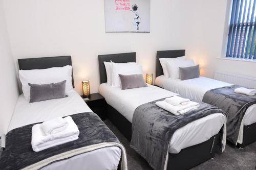 um quarto com três camas com toalhas em Executive 8 Beds 2 Bath Home Contractors Parking em Southampton