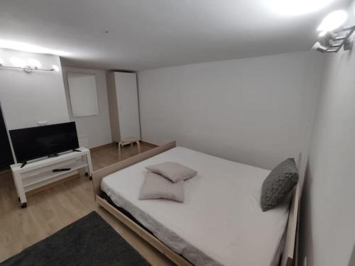 a white bedroom with a bed and a tv at super monolocale moderno in Gela