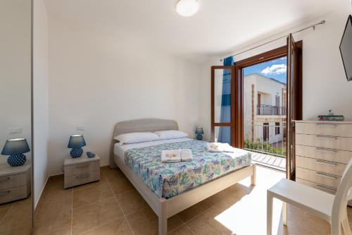 a white bedroom with a bed and a window at I Tre Golfi - Via Salvatore Quasimodo in San Vito lo Capo