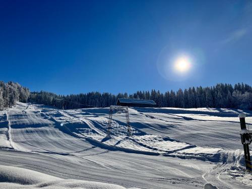 a snow covered slope with the sun in the sky at Ferienwohnung Bergblick am Rande der Wildnis in Sibratsgfäll