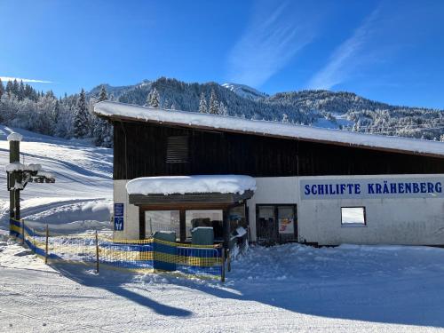 a building with snow on the side of it at Ferienwohnung Bergblick am Rande der Wildnis in Sibratsgfäll