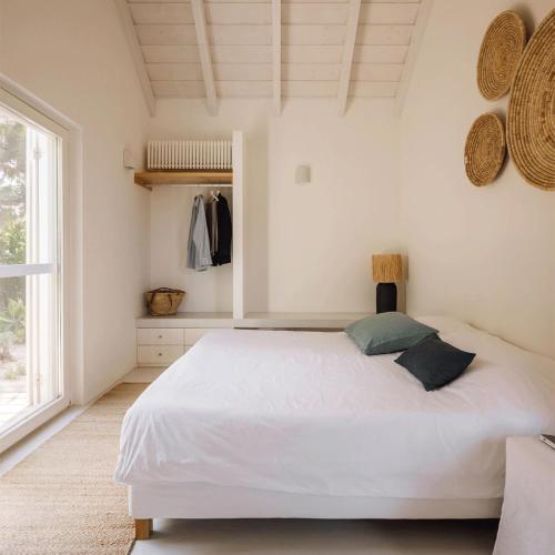 een slaapkamer met een wit bed en een raam bij Casas de Arroz in Comporta