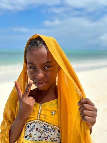 a young girl on the beach making a peace sign at TIANDE Boutique Hotel in Pwani Mchangani