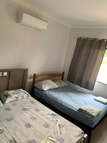 two twin beds in a room with a window at Rancho próximo ao lago de furnas in Boa Esperança