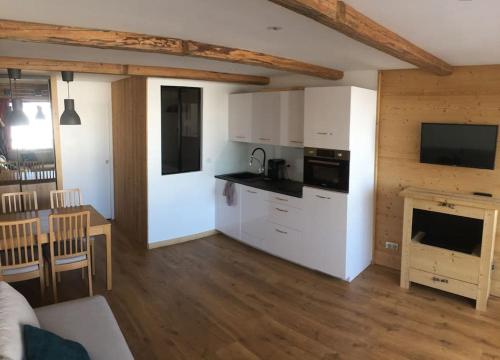 une cuisine avec des placards blancs, une table et une cheminée dans l'établissement Appartement de charme, ski aux pieds, pour 6 personnes, à Huez