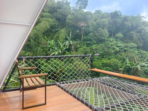 a balcony with a chair and a view of the forest at Selayang Olivehill - Kemewahan Glamping di Hutan 