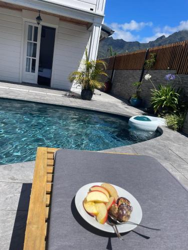 a plate of fruit on a table next to a swimming pool at Villa Ananda in Cilaos