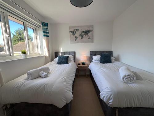 two twin beds in a room with two windows at Frensham House in Dallington