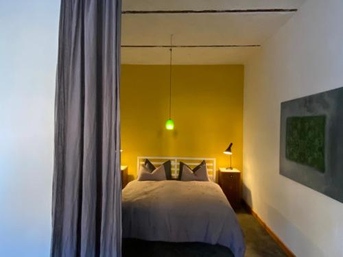 a bedroom with a bed and a yellow wall at Gasthof zum grünen Baum in Boitzenburg