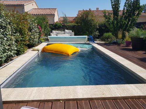 - une piscine avec un oreiller jaune dans l'eau dans l'établissement L'ETOURNEAU, à Bédoin