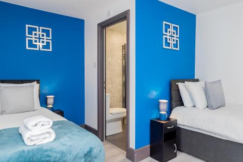 a blue bedroom with two beds and a mirror at Executive 8beds 3bath Contractorswelcome Parking in Southampton