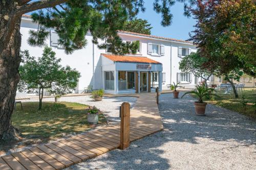 a building with a wooden walkway in front of it at Maison Esperanza hôtel et appartement in Noirmoutier-en-l'lle