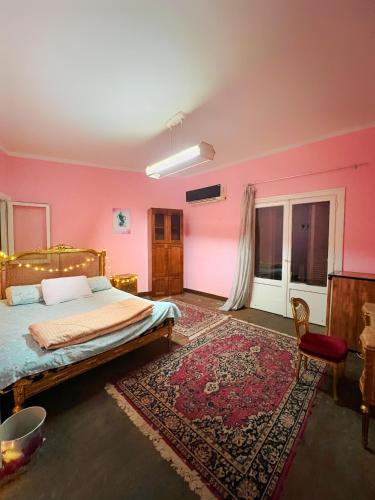 um quarto com paredes cor-de-rosa, uma cama e um tapete em Cozy room in the heart of cairo no Cairo