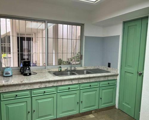 a green kitchen with a sink and a window at Espacioso, Centrico, Acogedor y Buena Ubicacion in Cancún