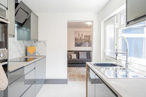 a white kitchen with a sink and a living room at Executive 8beds 3bath Contractorswelcome Parking in Southampton