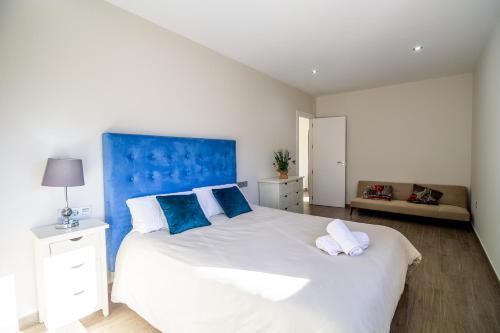 um quarto com uma grande cama branca e uma cabeceira azul em RentitSpain Las Fanegas Montañas de Alpujarra em Yátor