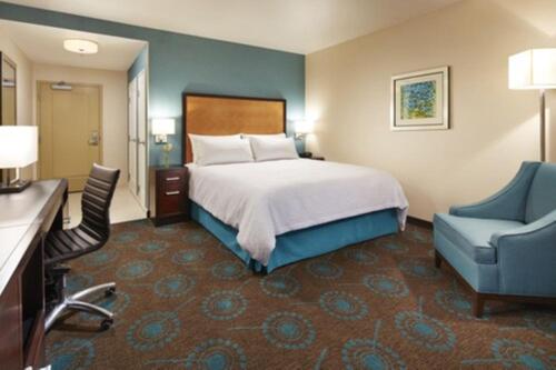 a hotel room with a bed and a blue chair at Hampton Inn San Diego Mission Valley in San Diego