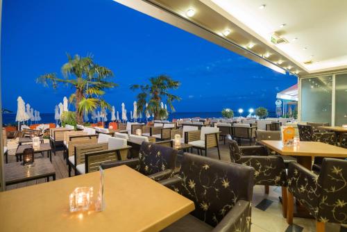 a restaurant with tables and chairs with the ocean in the background at Panorama Hotel in Paralia Katerinis