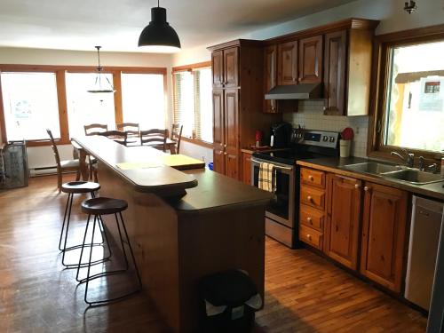 a kitchen with wooden cabinets and a kitchen island with bar stools at Le gîte du Lac à la Tortue in Herouxville