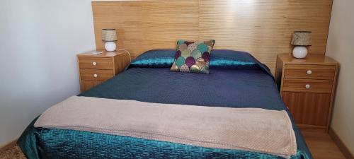 een slaapkamer met een bed met een houten hoofdeinde bij SUNSET REFUGE in Fajã da Ovelha