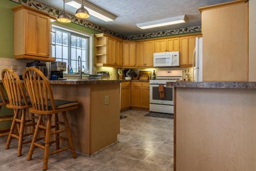 a kitchen with wooden cabinets and bar stools at Lake Manistee Lodge Ski & Snowmobile Hideout in Kalkaska