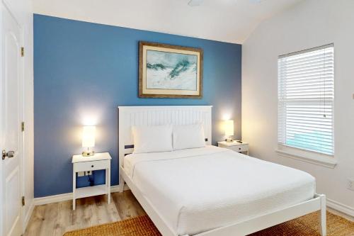 1 dormitorio con cama blanca y pared azul en Beach Haven Unit 201, en Corpus Christi