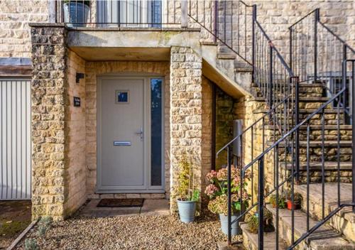a brick house with a door and stairs with plants at The Studio @ No. 6 in Brimscombe