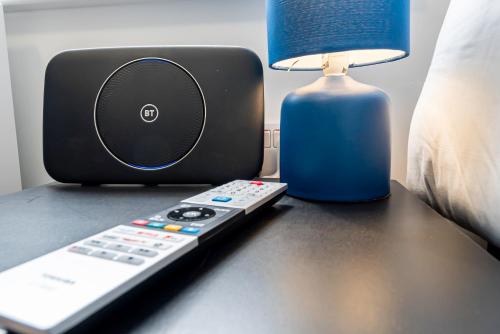 a remote control sitting next to a lamp and a speaker at Executive 8beds 3bath Contractorswelcome Parking in Southampton