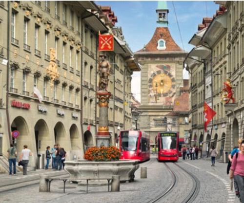 dos tranvías rojos en una calle en una ciudad en Ferienwohnung in Zentrale Lage, en Berna