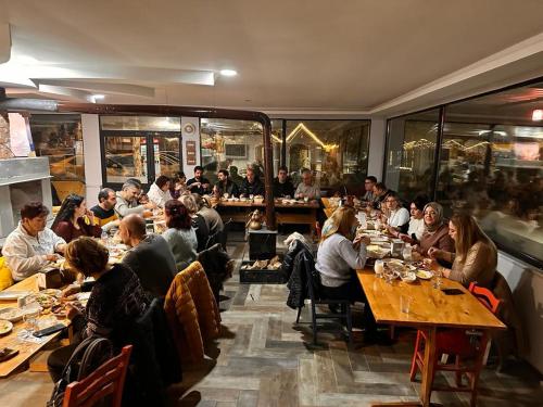een groep mensen die aan tafel zitten in een restaurant bij yuvacik kazli bahçe bungalov & taş otel in Yuvacık