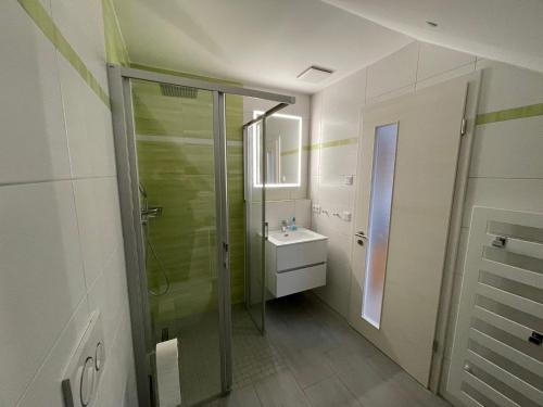 y baño con ducha acristalada y lavamanos. en Auszeit im Wald - mit Schwimmbad!, 