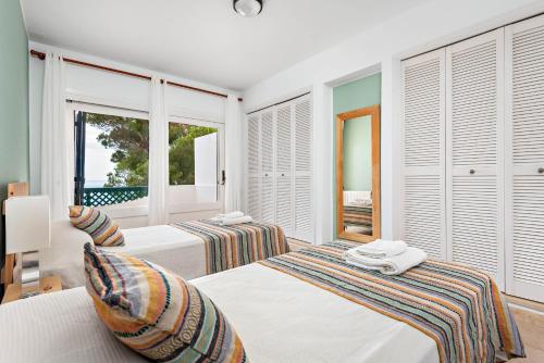 twee bedden in een kamer met ramen bij Villa Llevant Galdana in Cala Galdana