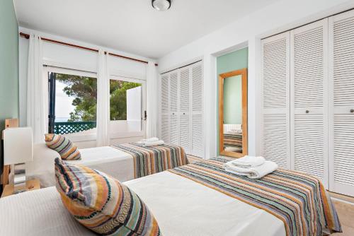 2 camas en una habitación con ventanas en Villa Llevant Galdana, en Cala Galdana