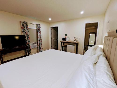 a bedroom with a large white bed and a television at The Honey Bee Motel in Dunlap