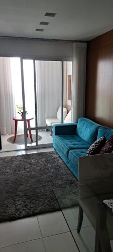 een woonkamer met een blauwe bank en een tafel bij Maravilhoso 2 quartos na Praia de Itaparica - Vila Velha in Vila Velha