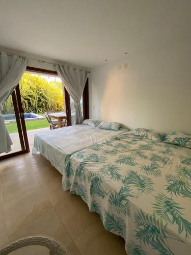 a bedroom with a bed and a large window at Taiba Beach Resort Casa com piscina in Taíba